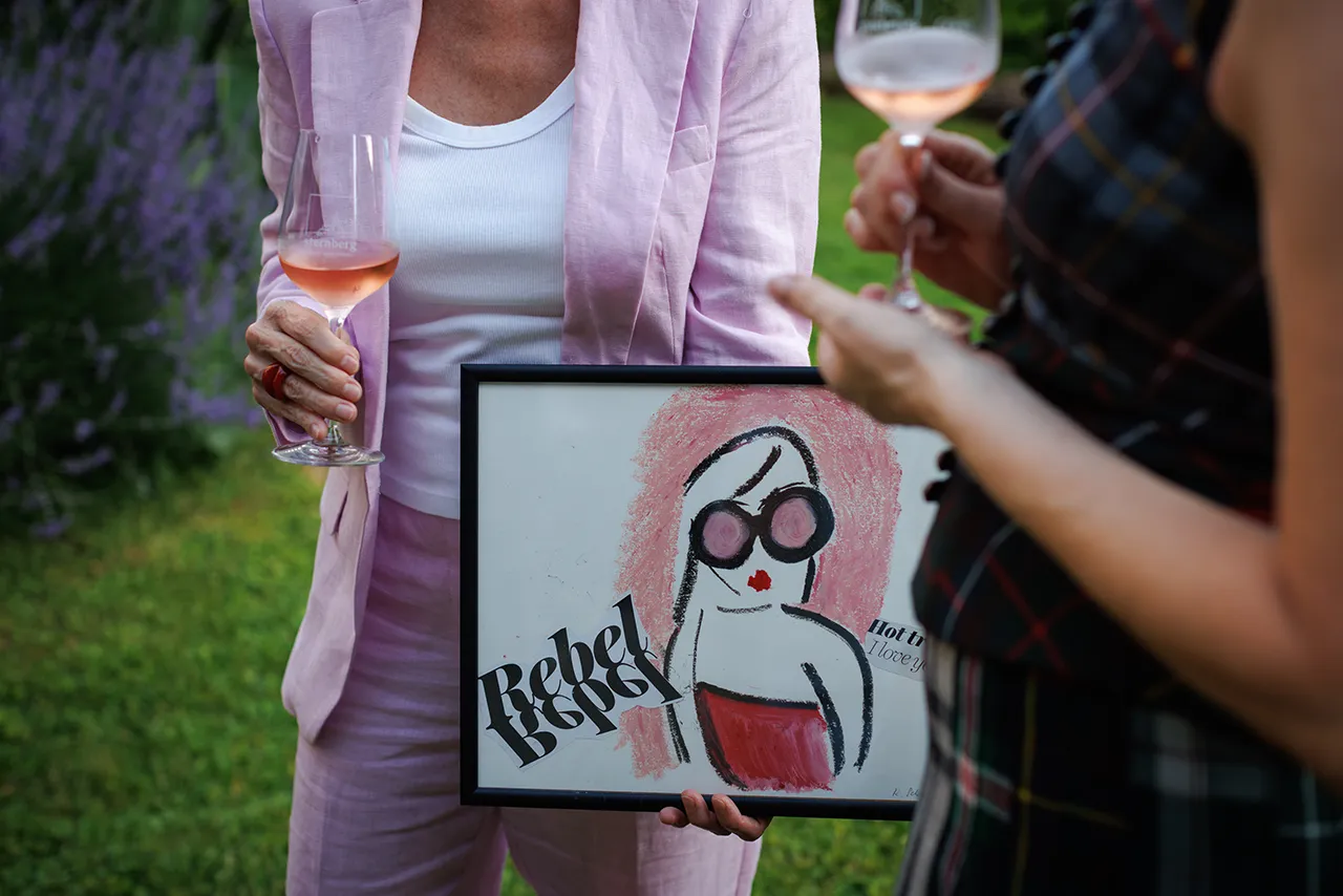 Künstlerin Romy Schwingenschuh präsentiert die Banderole für den Frizzante Rosé 2025.