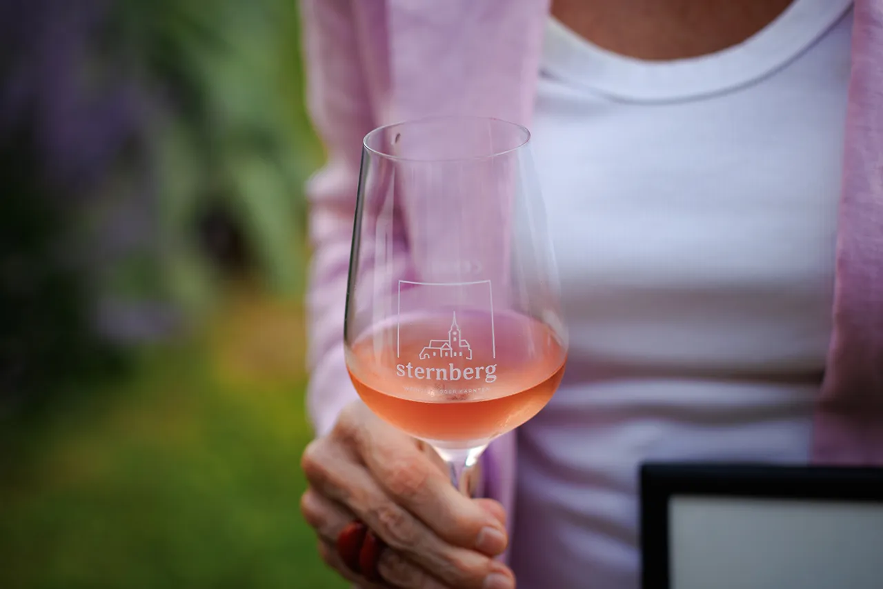 Künstlerin Romy Schwingenschuh mit einem Glas Frizzante Rosé 2025.
